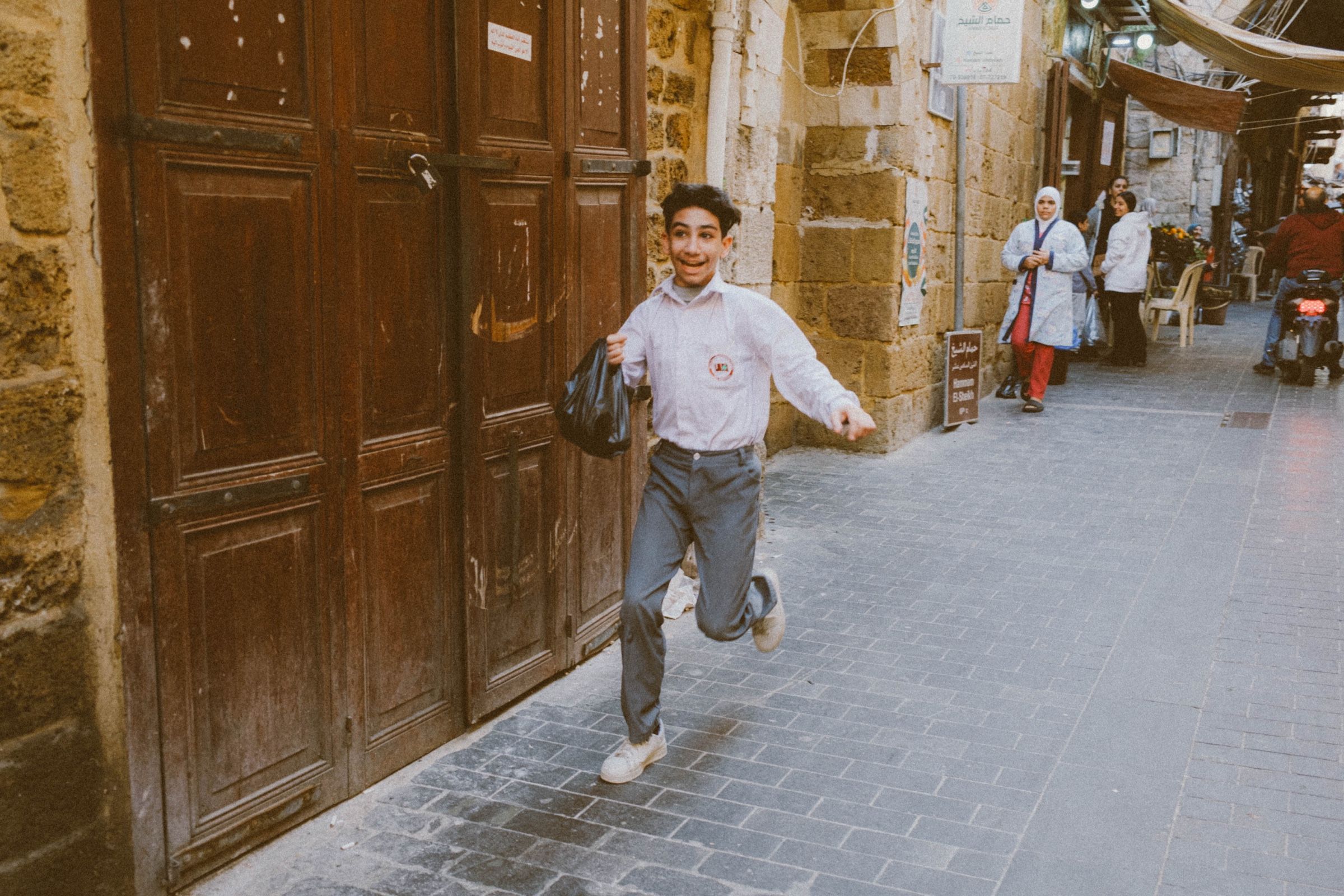 A candid photo of a young boy happily running in one of Sidon’s old streets, 2024.