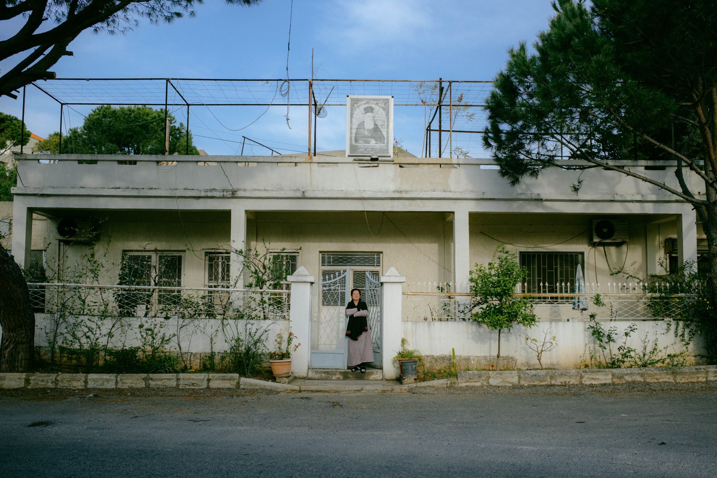 A portrait of an elderly woman in front of her home in the town of Joun, Lebanon, 2025.