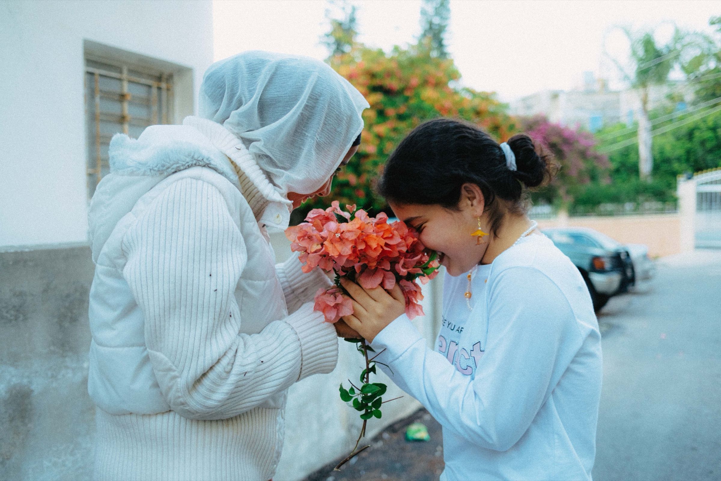 A candid photo of two friends holding a flower in the town of Joun, Lebanon, 2024.