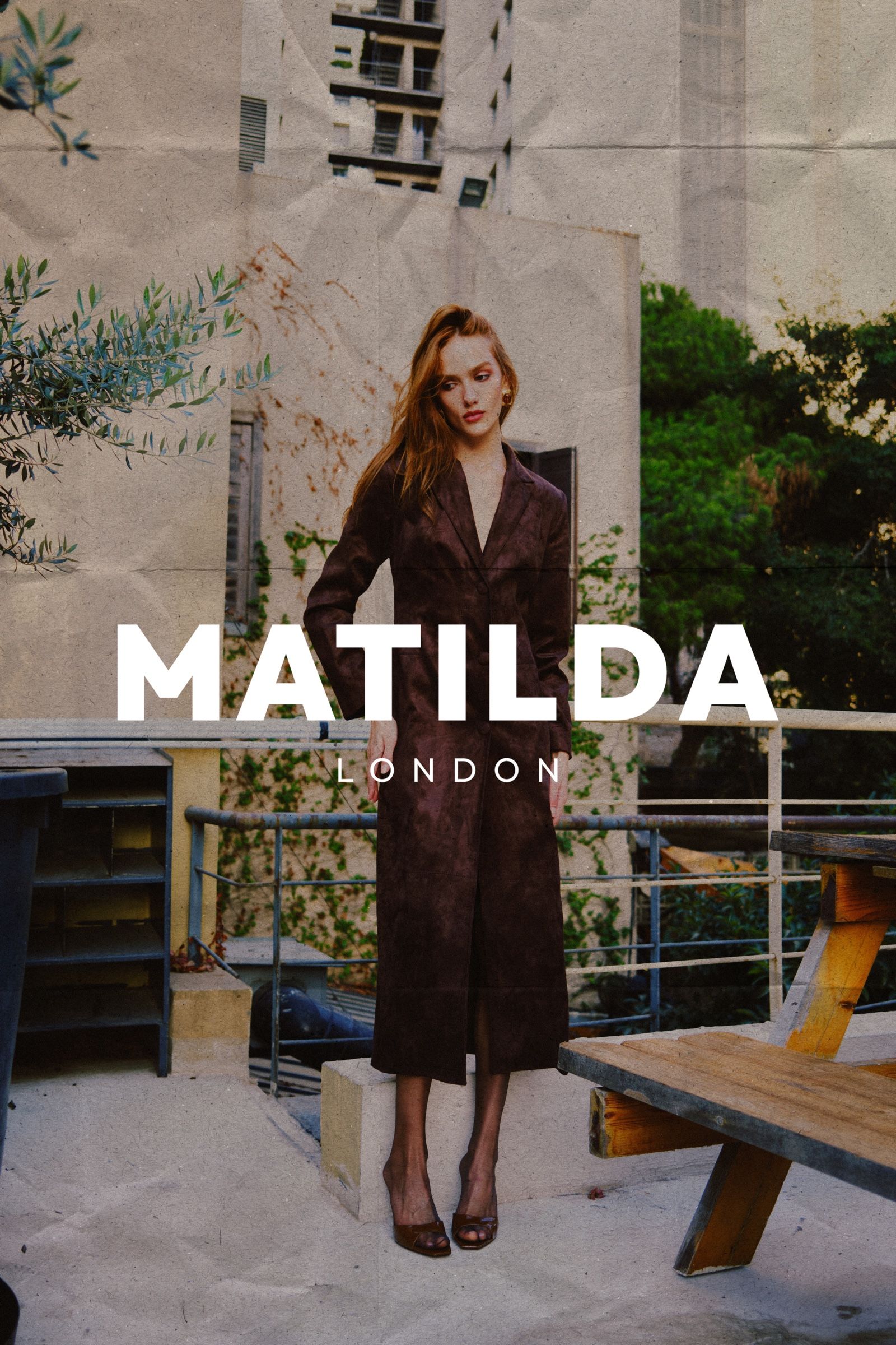 A model in a long brown suede coat stands on a concrete terrace, the story's title set in white capitals across the frame.