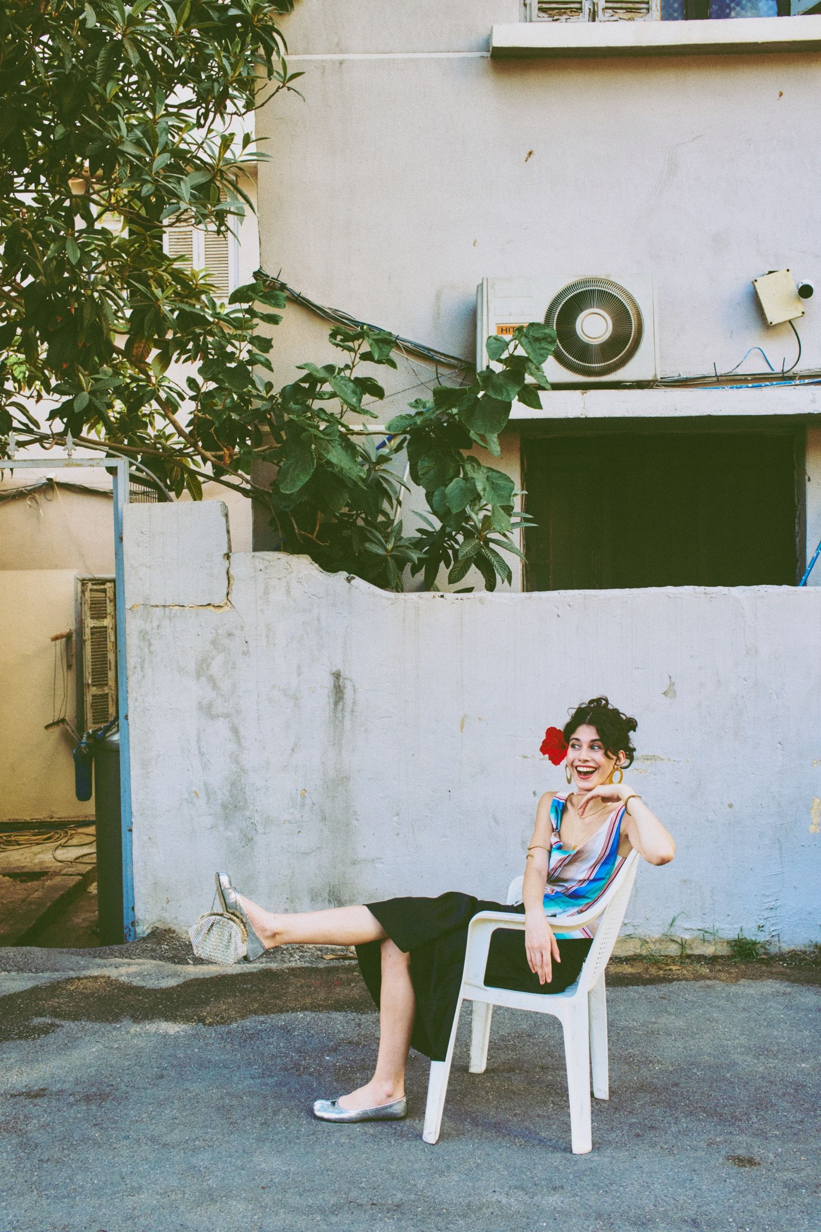 Reclining in the plastic chair, the model laughs off to one side, one leg kicked out, a beaded purse dangling from her raised silver flat.
